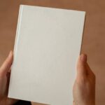 Meet New People - Person holding hardcover book with blank cover