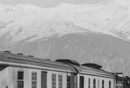 Overnight Train - A black and white photo of a train with snow capped mountains in the background